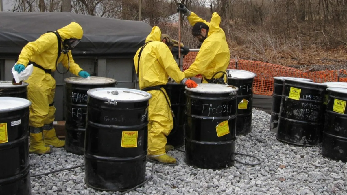 Hazmat workers handling lead-contaminated soil waste drums