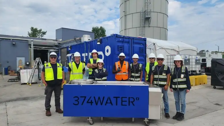 374Water team in hard hats beside branded blue treatment unit